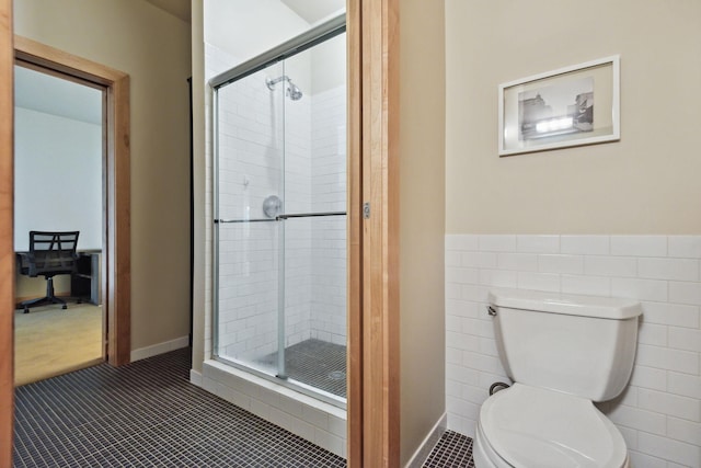 bathroom with tile walls, a shower with shower door, toilet, and tile patterned floors