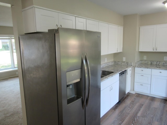 kitchen with dark hardwood / wood-style floors, sink, white cabinetry, stainless steel appliances, and light stone countertops