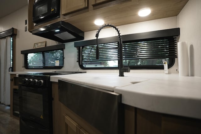 kitchen featuring black appliances, light stone countertops, and extractor fan