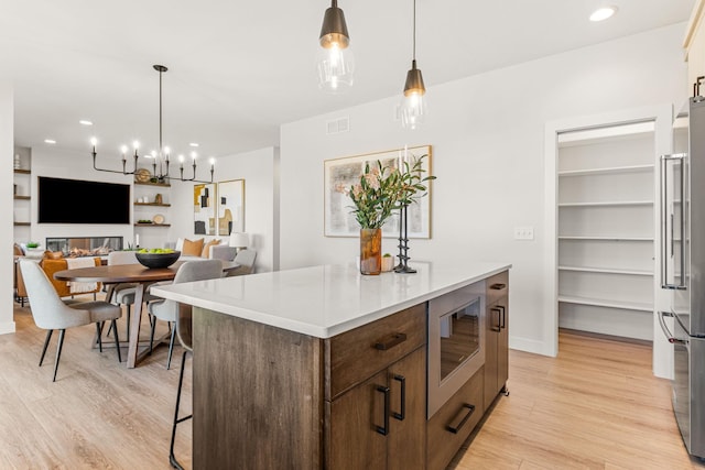 kitchen with built in microwave, high end refrigerator, a center island, and hanging light fixtures