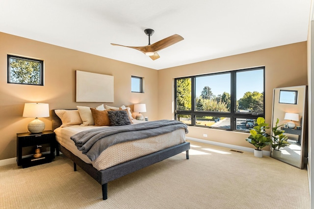 bedroom with light carpet, a ceiling fan, visible vents, and baseboards