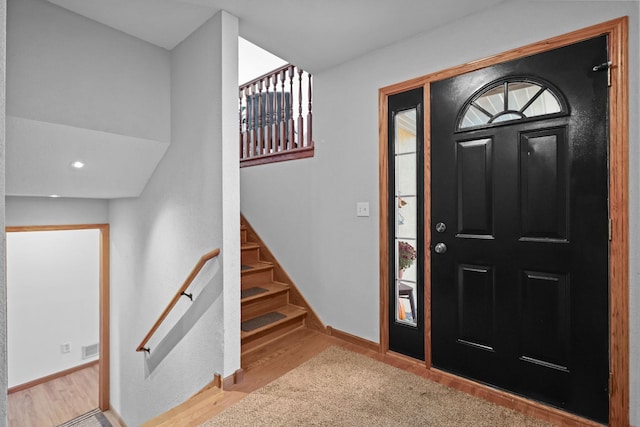 entrance foyer featuring stairs, visible vents, wood finished floors, and baseboards