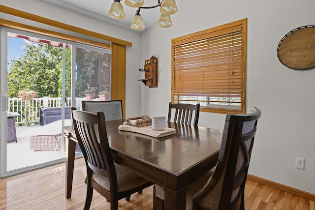 dining space featuring light wood-type flooring, plenty of natural light, baseboards, and a chandelier