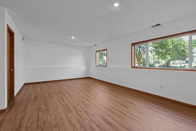 spare room with recessed lighting, visible vents, baseboards, and wood finished floors