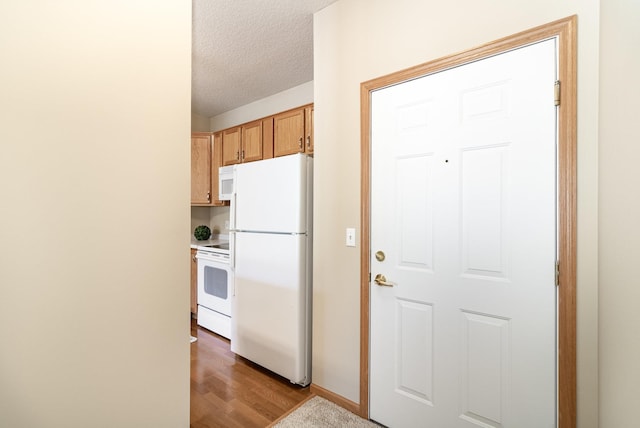 kitchen featuring light hardwood / wood-style floors, a textured ceiling, and white appliances