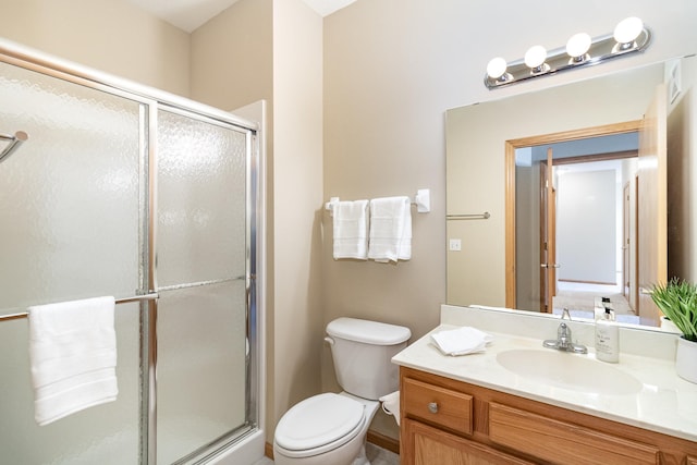 bathroom featuring vanity, toilet, and a shower with shower door