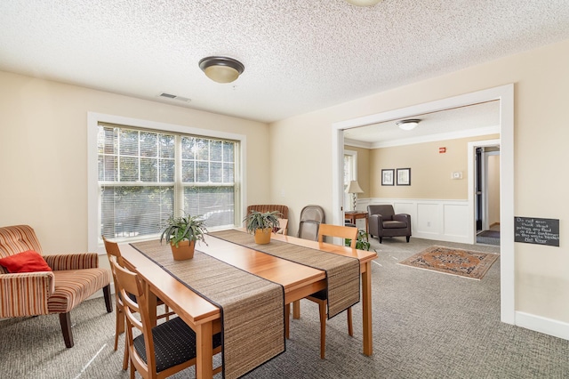 carpeted dining area with a textured ceiling