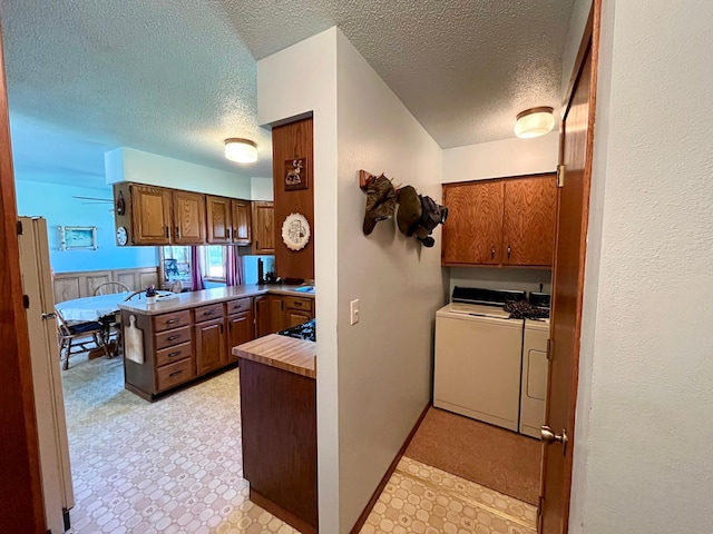 interior space with a textured ceiling, independent washer and dryer, kitchen peninsula, and gas cooktop