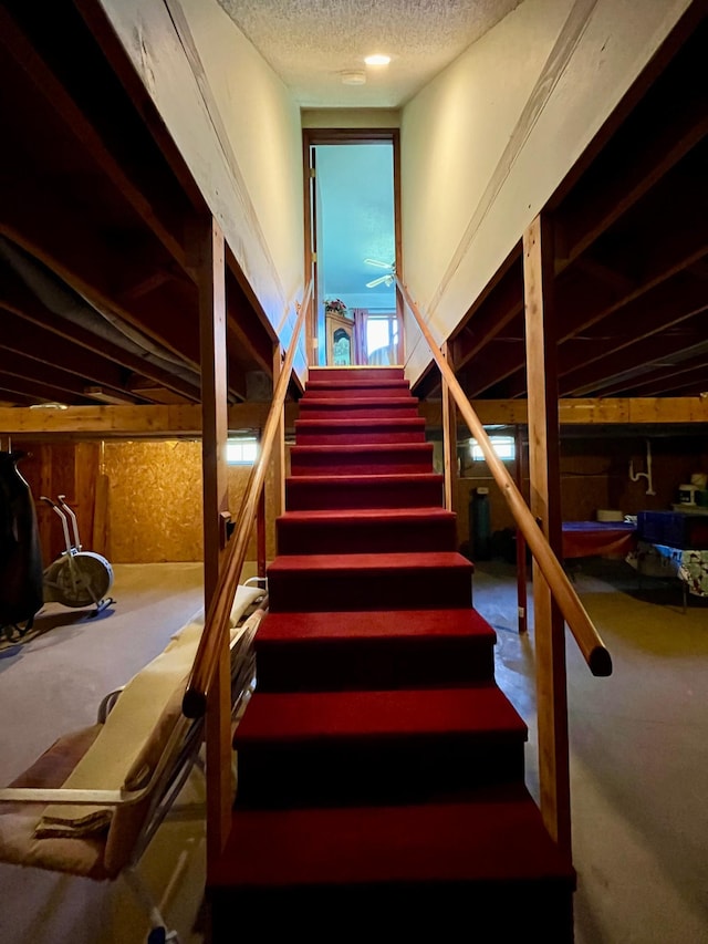 stairway with a textured ceiling and carpet floors