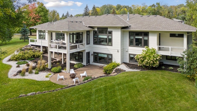 rear view of house with a balcony, a patio, and a yard