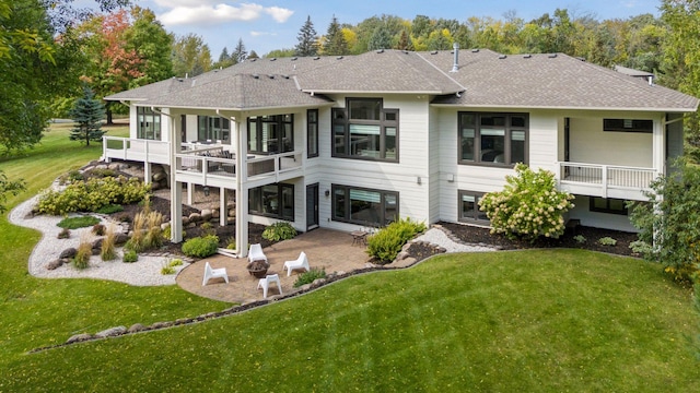 back of house with a yard, a patio, roof with shingles, and a balcony
