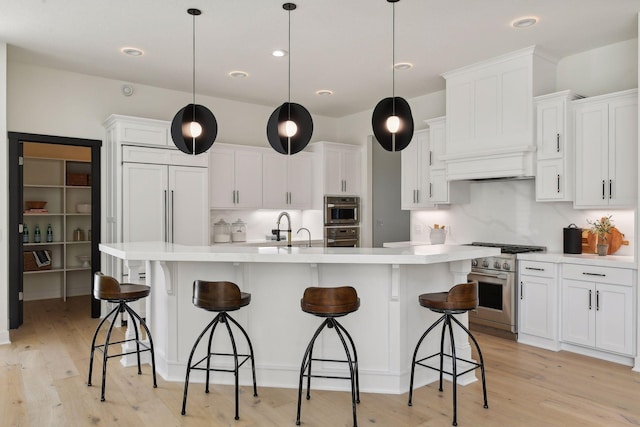 kitchen featuring white cabinets, light countertops, high quality appliances, and light wood-style floors