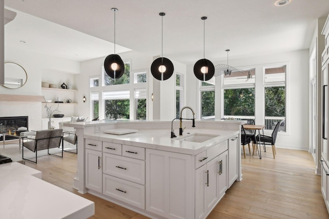 kitchen with a sink, open floor plan, light countertops, and white cabinets