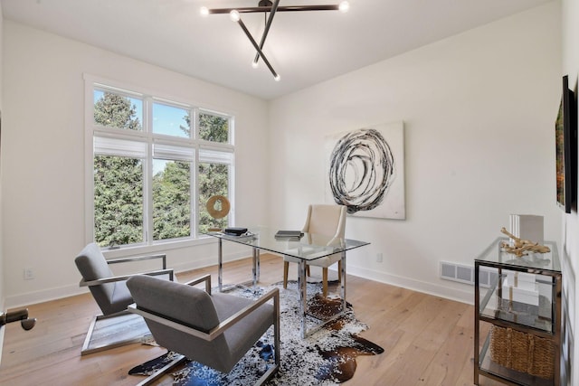 office space featuring baseboards, light wood-type flooring, and visible vents