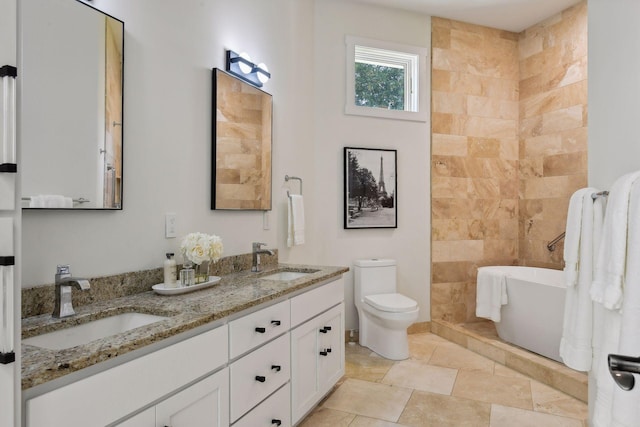 bathroom with double vanity, toilet, a freestanding tub, and a sink