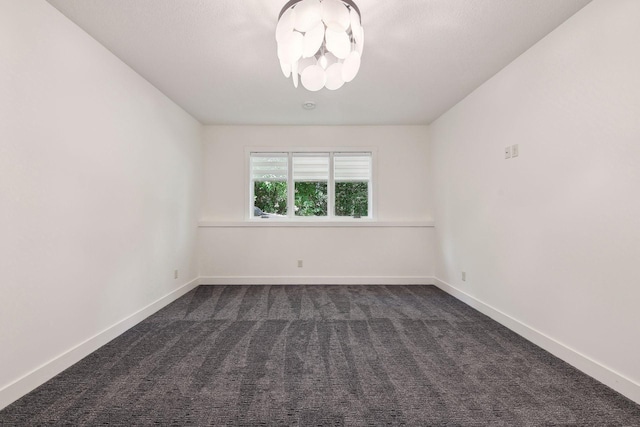 unfurnished room featuring an inviting chandelier, baseboards, and dark carpet