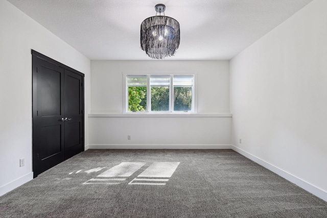 unfurnished bedroom featuring an inviting chandelier, a closet, baseboards, and carpet floors