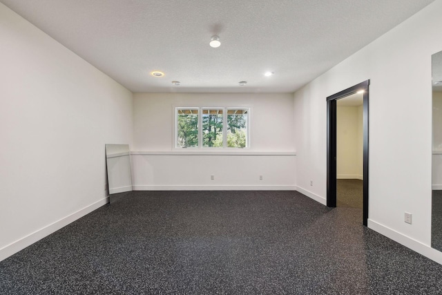 empty room featuring a textured ceiling, baseboards, dark speckled floor, and recessed lighting