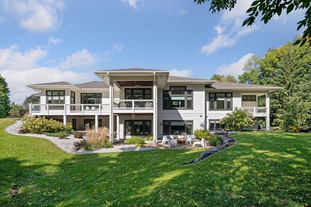 rear view of house featuring a balcony, ceiling fan, a patio, and a lawn