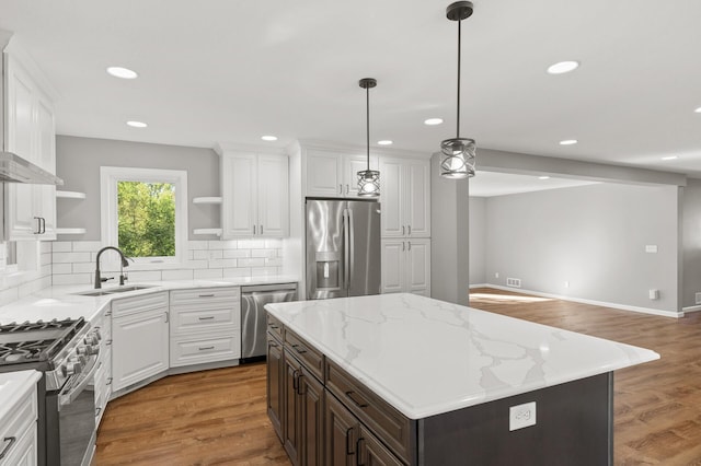 kitchen featuring appliances with stainless steel finishes, white cabinetry, a kitchen island, dark hardwood / wood-style flooring, and sink