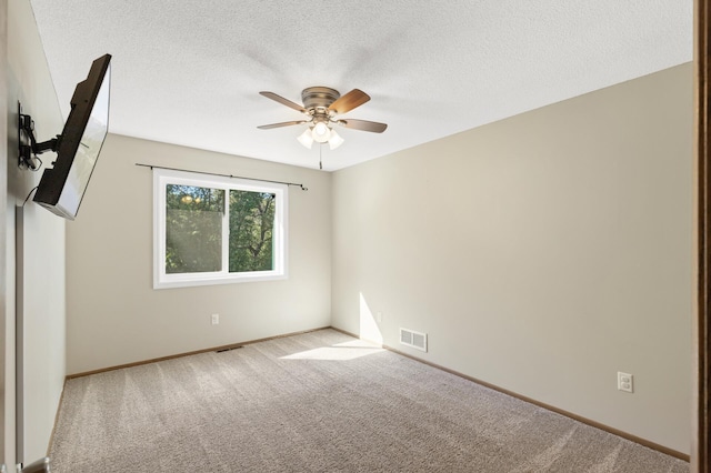 empty room with light carpet, ceiling fan, and a textured ceiling