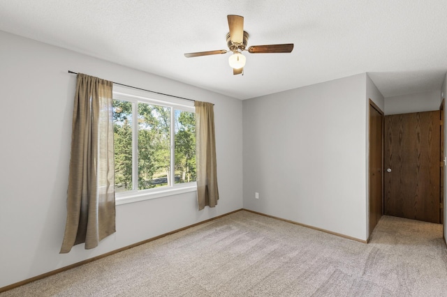 carpeted spare room with a textured ceiling and ceiling fan