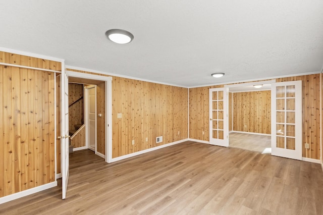 basement with wood walls, hardwood / wood-style flooring, french doors, and crown molding