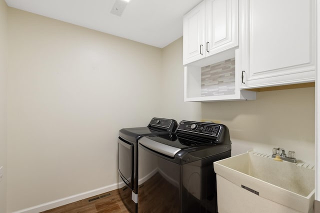 clothes washing area featuring dark hardwood / wood-style flooring, independent washer and dryer, cabinets, and sink