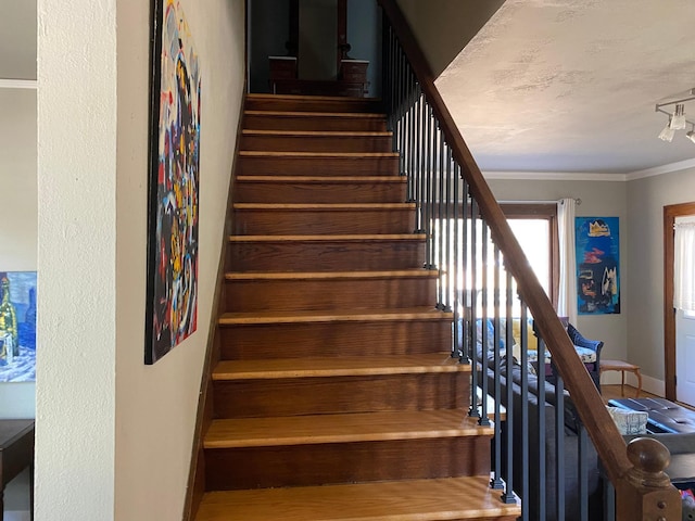 stairs featuring crown molding and track lighting