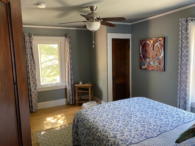 bedroom with ornamental molding, ceiling fan, light wood-type flooring, and baseboards