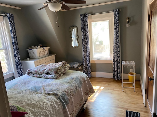 bedroom with crown molding, light hardwood / wood-style floors, vaulted ceiling, and ceiling fan