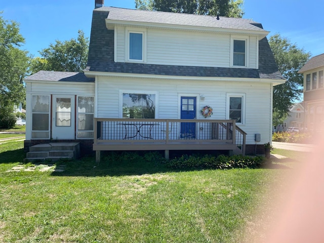 view of front of home with a chimney, a shingled roof, a front yard, and a deck