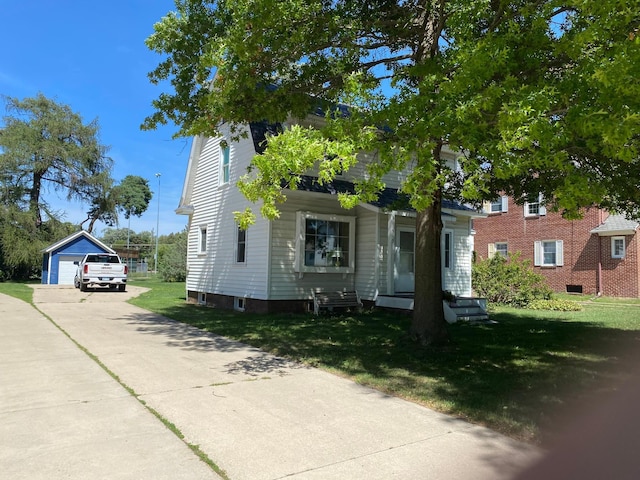 view of front of home with a front yard, a garage, and an outbuilding