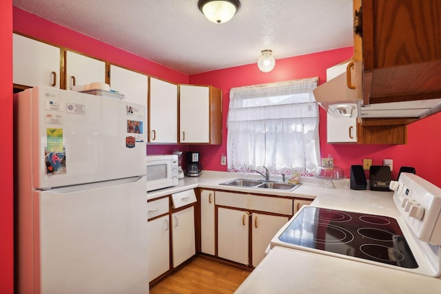 kitchen with sink, white cabinetry, a textured ceiling, white appliances, and light hardwood / wood-style floors