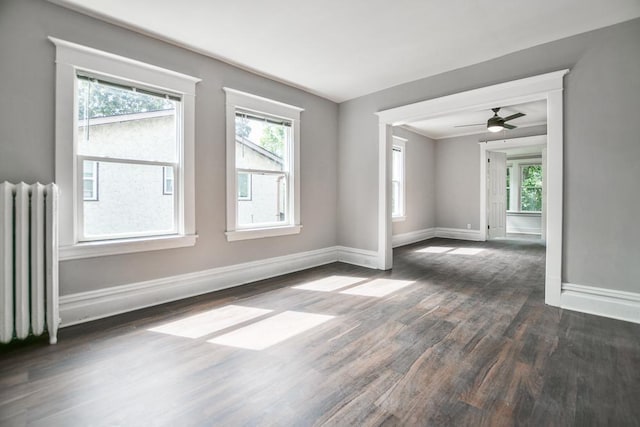 unfurnished room with ceiling fan, radiator, and dark hardwood / wood-style flooring