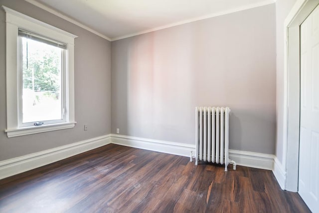 spare room with crown molding, radiator, and dark wood-type flooring