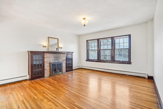 unfurnished living room with light hardwood / wood-style flooring, a baseboard heating unit, a fireplace, and a textured ceiling