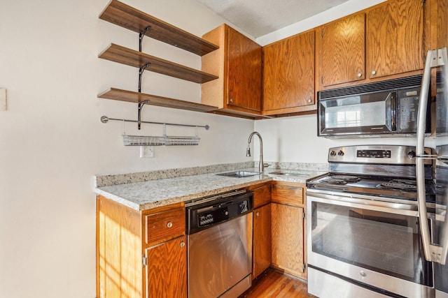 kitchen featuring light stone counters, sink, light wood-type flooring, and appliances with stainless steel finishes