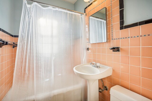 bathroom with toilet, a shower with shower curtain, and tile walls