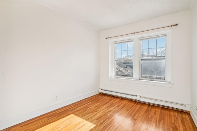 unfurnished room featuring a baseboard radiator and light hardwood / wood-style floors