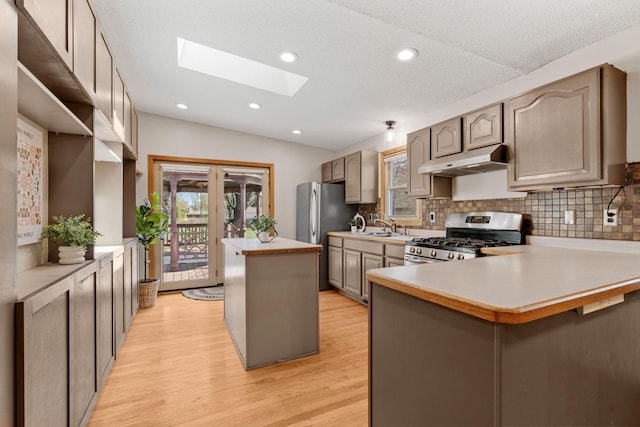 8011 Long Lake Rd, Mounds View, MN 55112 - kitchen featuring stainless steel appliances, under cabinet range hood, a skylight, light wood-type flooring, and a center island