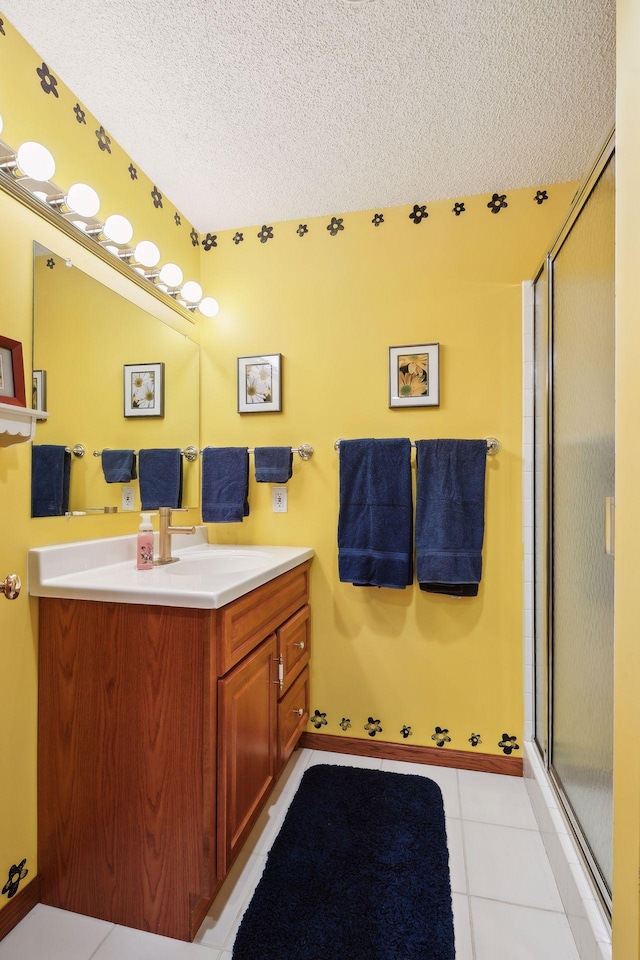 bathroom featuring vanity, a textured ceiling, a shower with shower door, and tile patterned floors