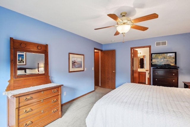 bedroom featuring ceiling fan, light colored carpet, and ensuite bath