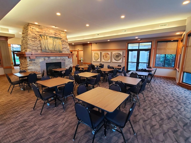 carpeted dining space with a stone fireplace