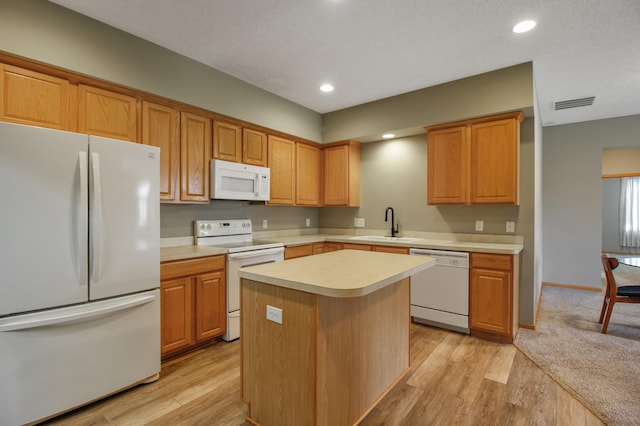 kitchen featuring white appliances, a center island, sink, and light wood-type flooring