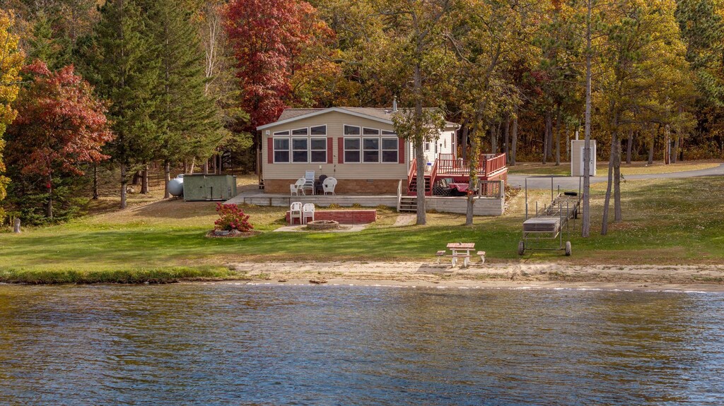 rear view of property featuring a deck with water view and a yard