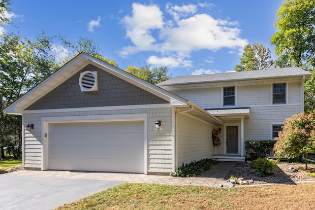 traditional home featuring a garage, roof with shingles, and aphalt driveway