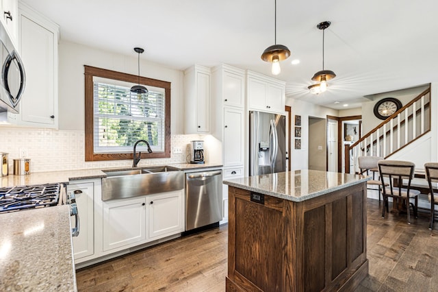 kitchen featuring stainless steel appliances, white cabinets, a sink, and dark wood-style floors