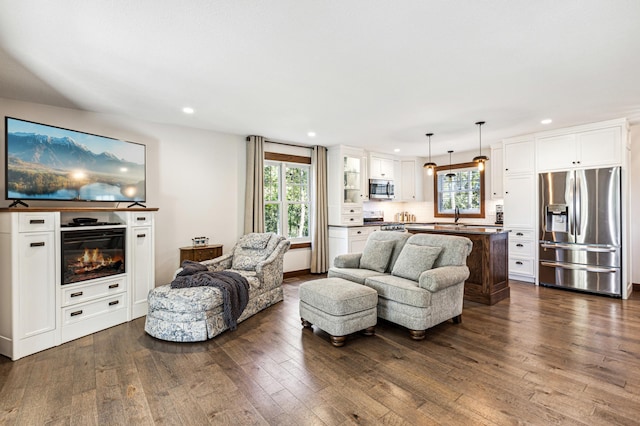 living area with a glass covered fireplace, dark wood-style flooring, and recessed lighting