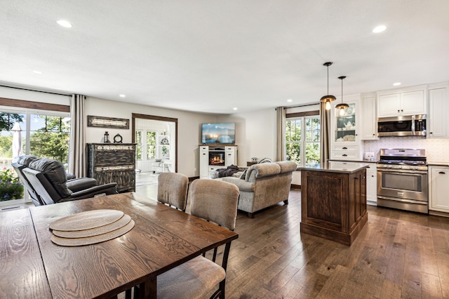 dining room featuring dark wood-style floors, recessed lighting, and a lit fireplace